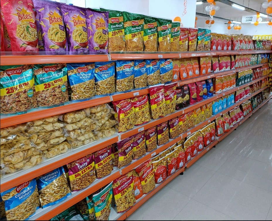 Rows of packaged snacks, namkeens, and potato chips stacked on supermarket shelves