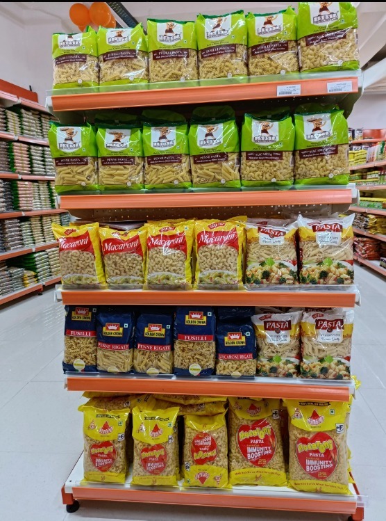 A display stand filled with macaroni packages, penne pasta, and instant food items