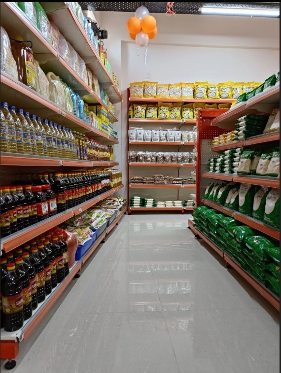 Neatly stacked bags of flour, grain packages, and bottles of cooking oil in a staples aisle